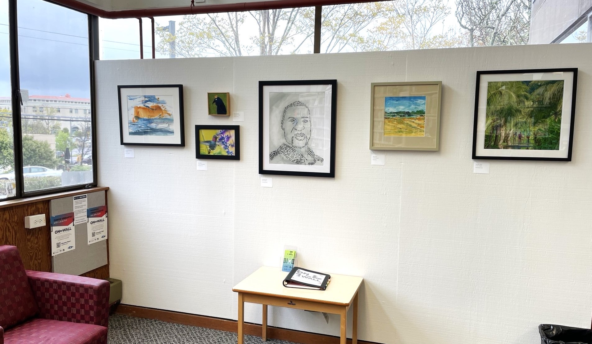 Works of art are displayed on the wall of a library.