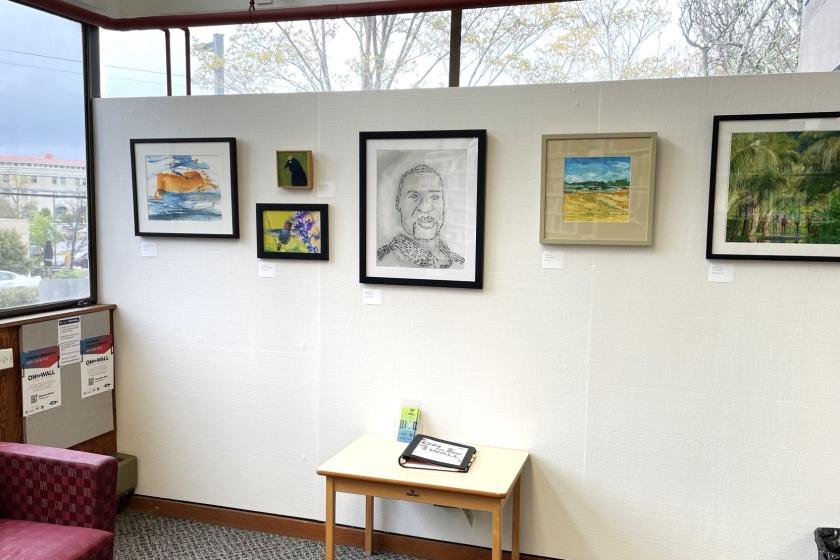 Works of art are displayed on the wall of a library.