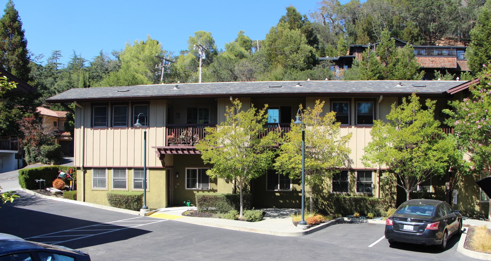 Two story multi-unit building with a driveway and parking surrounding the building.